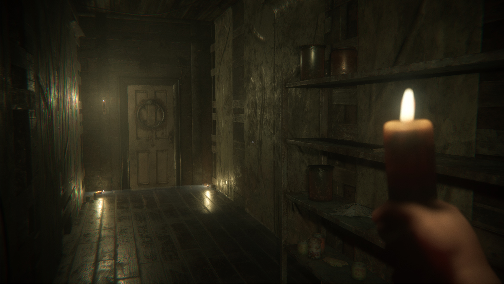 A first-person view holding a candle in a narrow wooden corridor