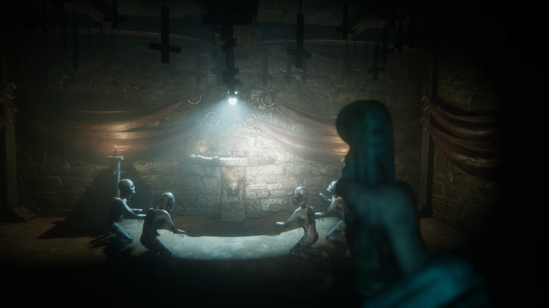 A candlelit stone ritual chamber with suspended crosses and kneeling figures